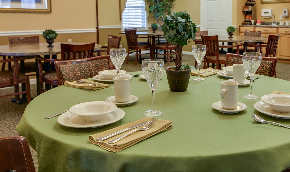 An elegantly set dining table in a restaurant with neatly arranged tableware and a centerpiece plant.