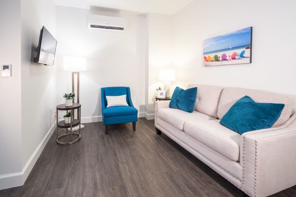 A modern living room with a white sofa, blue armchair, and chic decor.