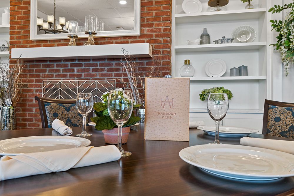 An elegantly set dining table with wine glasses, napkins, and a menu in a cozy restaurant interior.