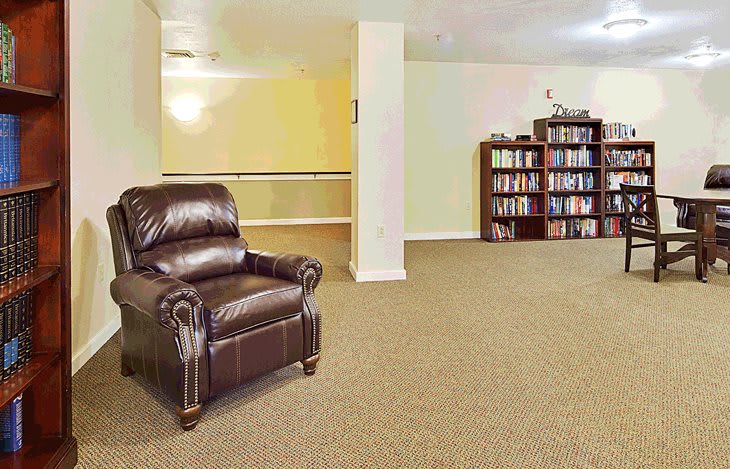 A cozy living room with a leather chair and a fully stocked bookshelf.