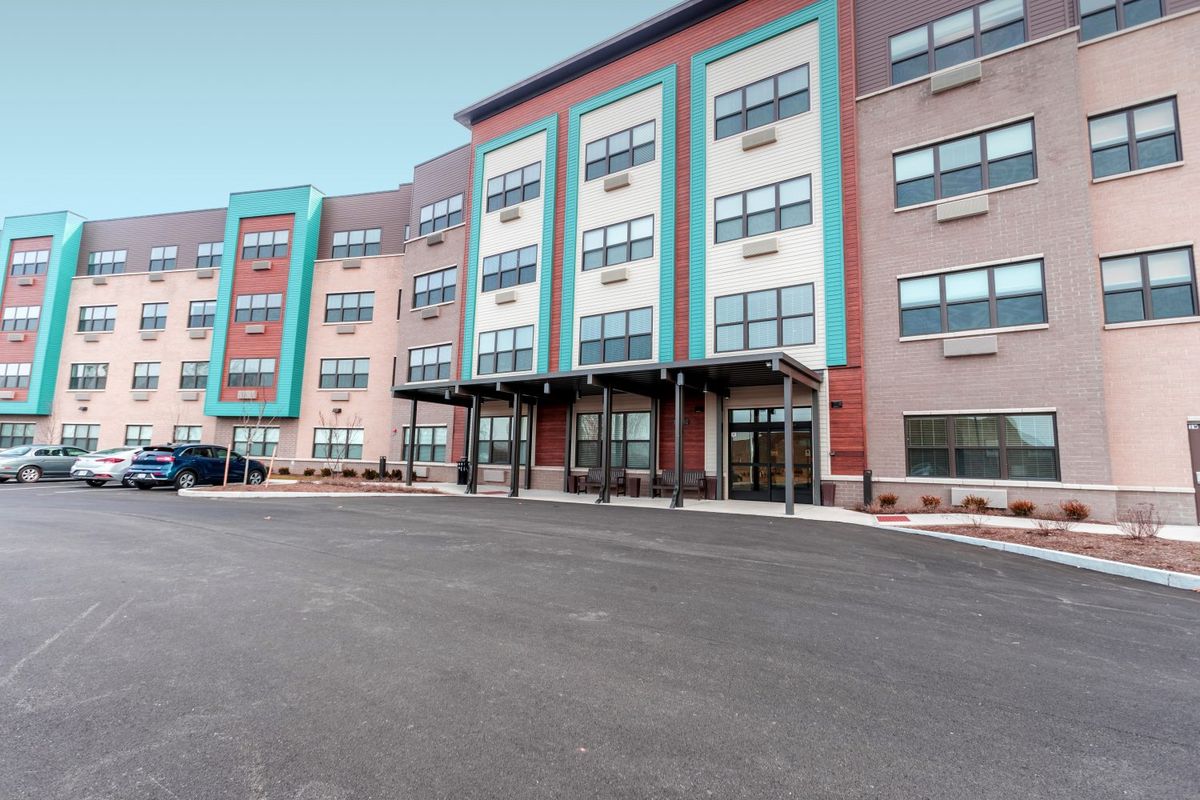 A modern, multi-story apartment building with colorful accents and large windows.