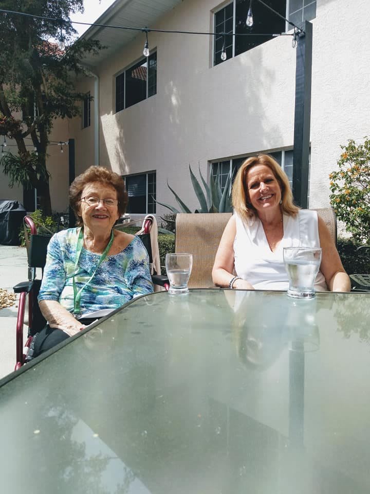 Two women sitting at a table outside, enjoying a sunny day.
