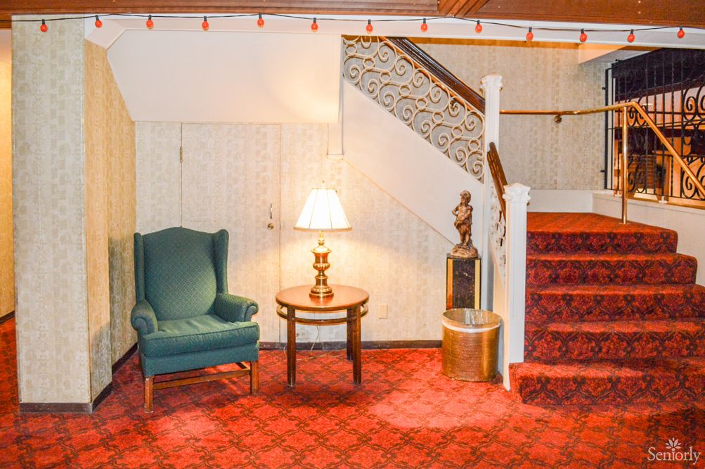 Cozy interior with a staircase, armchair, and a lamp on a side table.