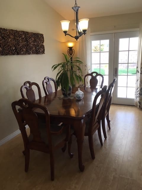 A cozy dining room with a wooden table and elegant chairs, accented by a plant centerpiece and soft lighting.