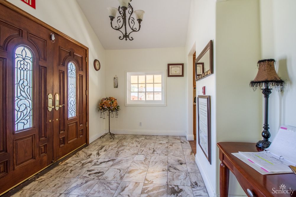 A well-lit foyer with marble flooring, a wooden front door, and elegant decor.