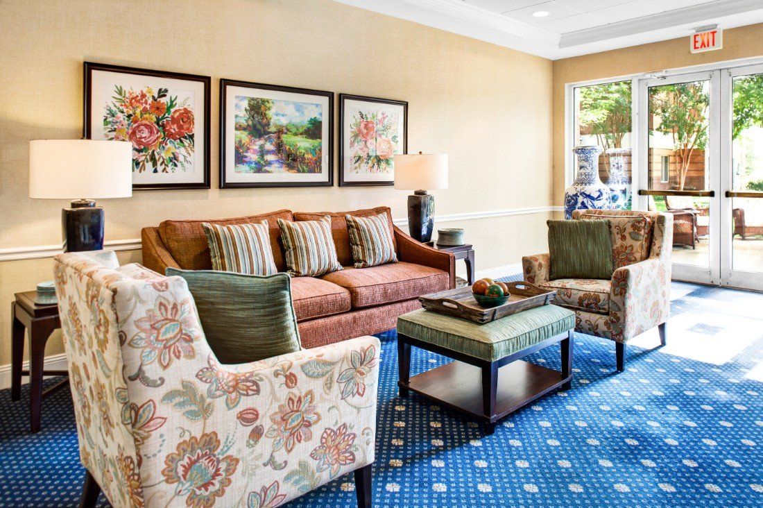 A cozy living room with a sofa, two armchairs, and a coffee table, adorned with decorative artwork on the walls.