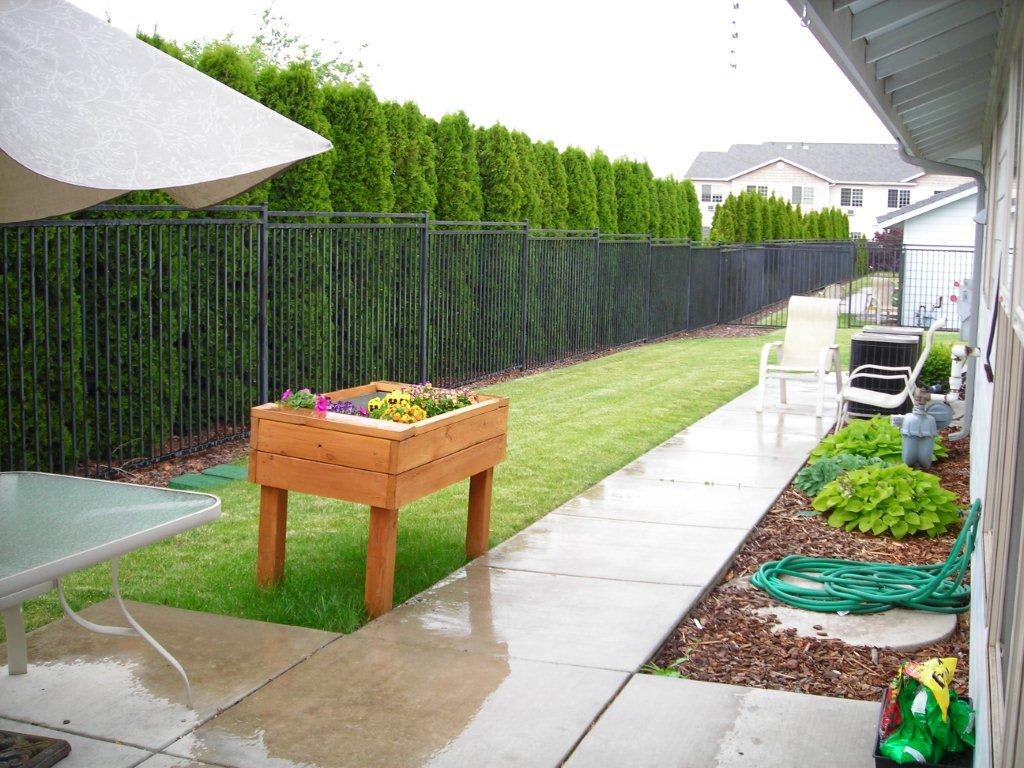A suburban backyard featuring a raised garden planter and a well-maintained lawn.