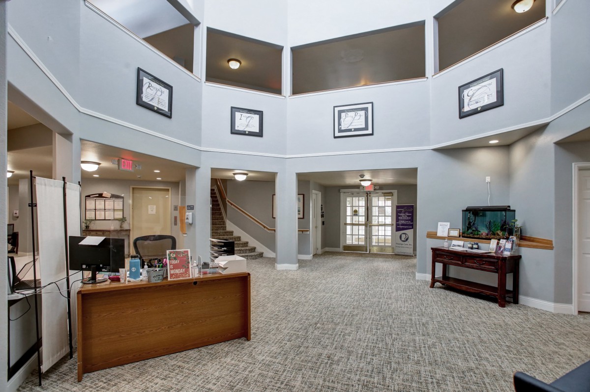 A spacious office lobby with a central desk, carpet flooring, and staircase leading to an upper level.