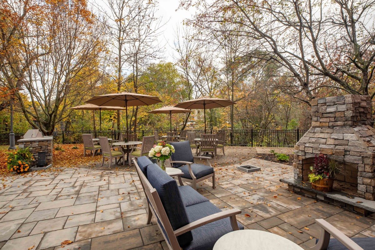 A cozy outdoor patio with seating and umbrellas surrounded by autumn trees.