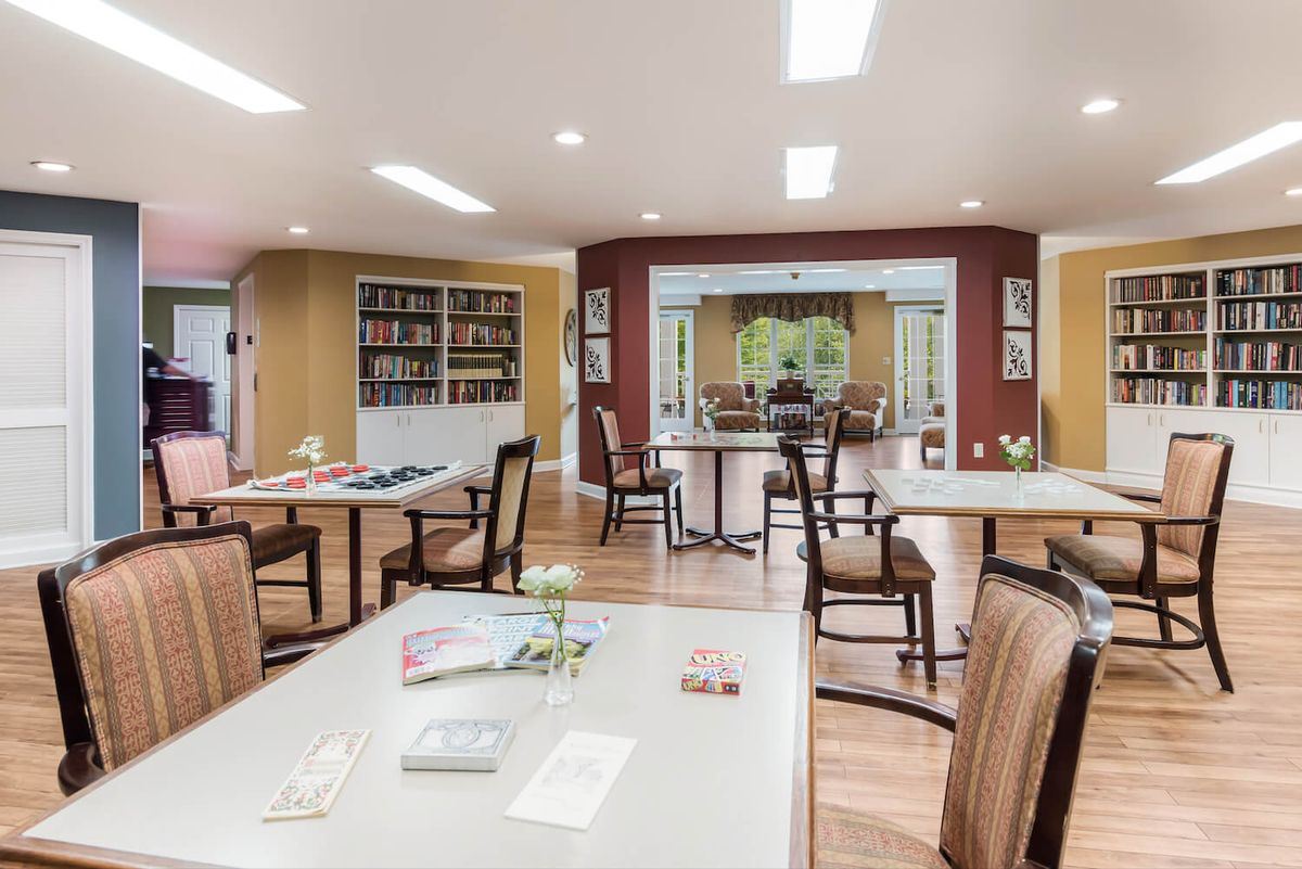A well-lit library reading area with tables, chairs, and bookshelves.