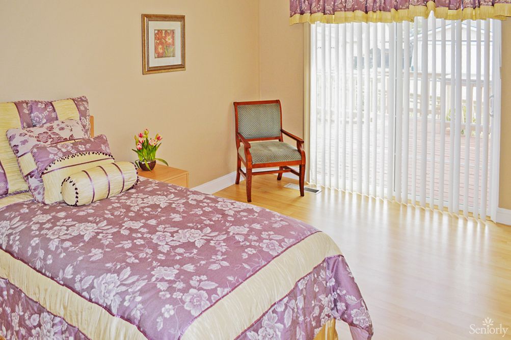 A cozy bedroom featuring a floral bedspread and natural light streaming through the curtains.