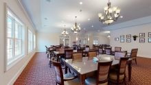 A spacious dining room with multiple tables and elegant chandeliers.