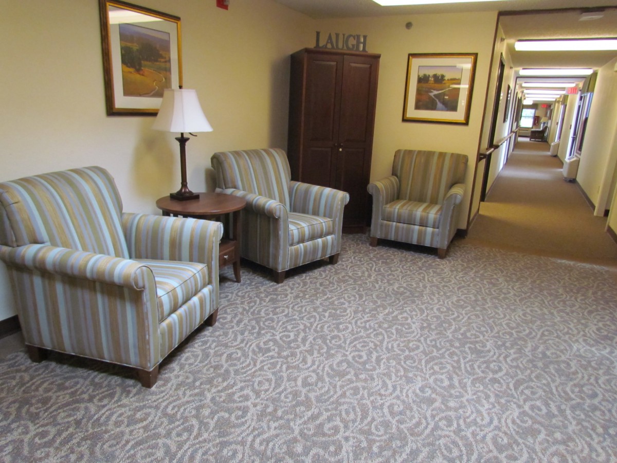 A cozy seating area in a hallway with striped chairs, a lamp, and artwork on the walls.