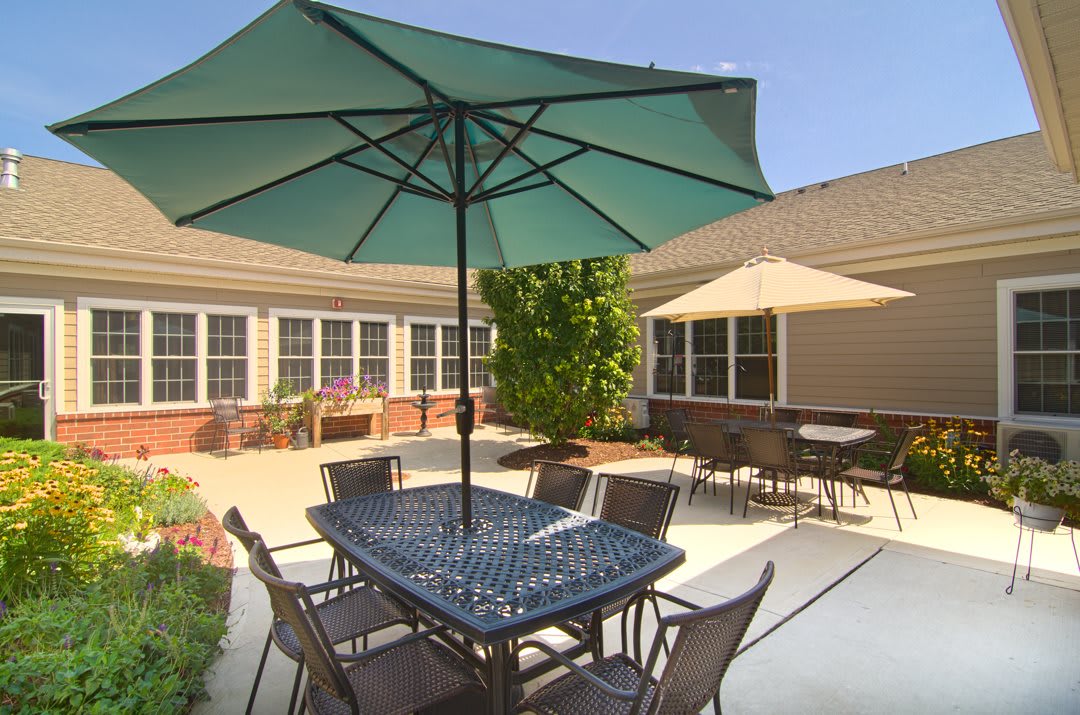 A sunny patio area with tables, chairs, and large umbrellas.