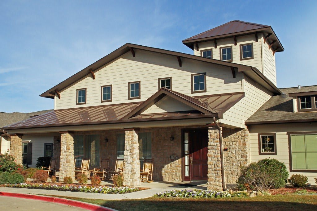 A two-story residential house with a stone exterior and a spacious porch.