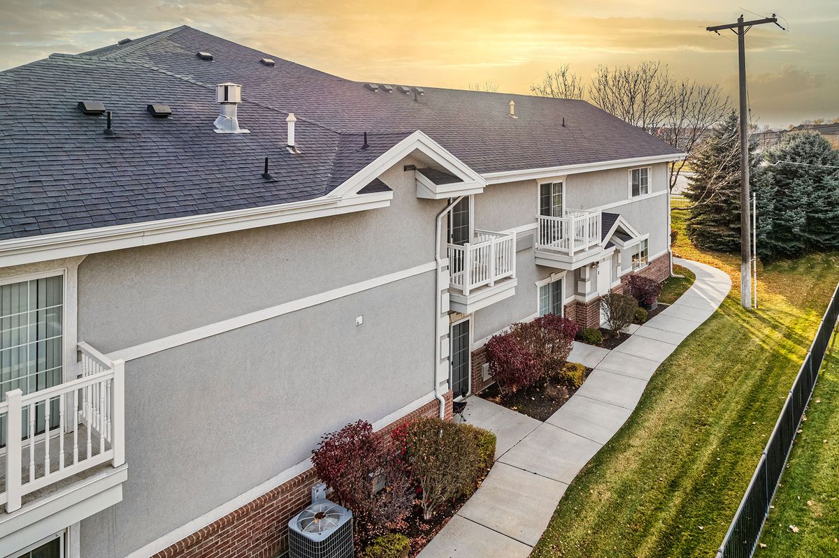 Sunset view of a suburban apartment building with a well-maintained lawn and sidewalk.