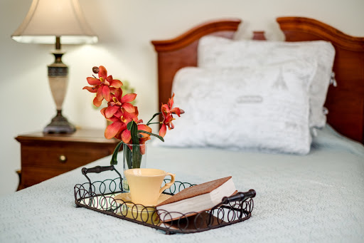 A cozy bedside setup featuring a decorative tray with a cup, book, and fresh flowers.