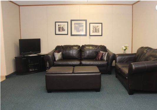 A cozy living room with leather sofas, a coffee table, and a TV.