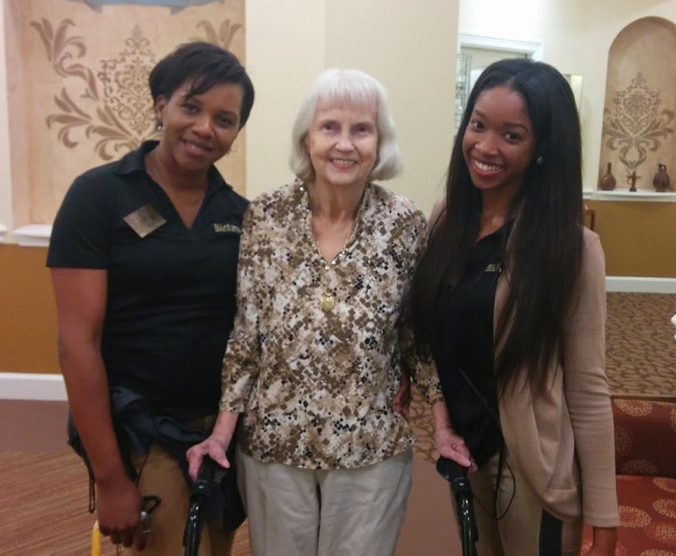 Three women posing together and smiling indoors.