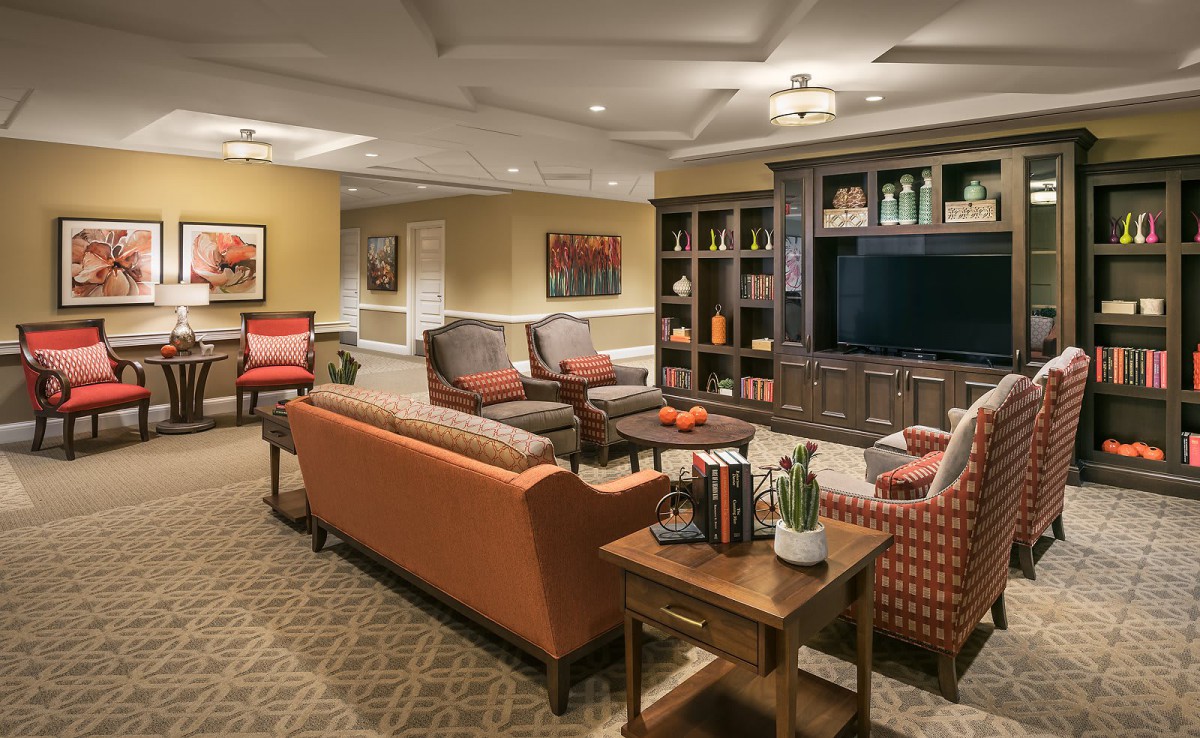 A cozy living room featuring comfortable seating, a large television, and a well-organized bookshelf.