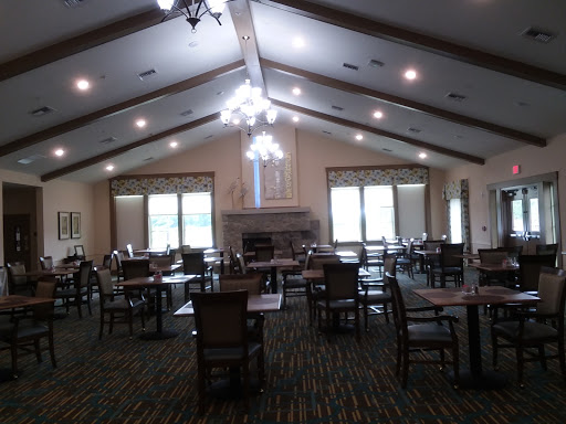 A spacious dining area with tables and chairs, featuring large windows that let in natural light.