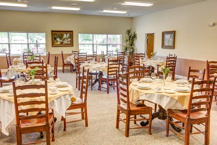 An empty dining room with neatly set tables and wooden chairs.