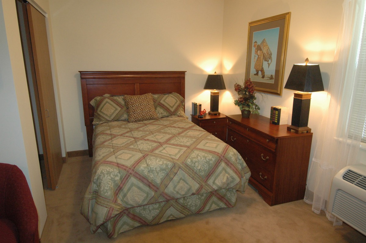 A cozy bedroom with a neatly made bed and matching nightstands adorned with lamps and a decorative painting.