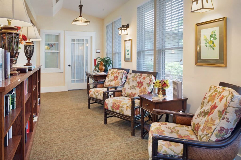 A cozy waiting room with floral-patterned chairs and soft lighting, complemented by a window view and decorative elements.
