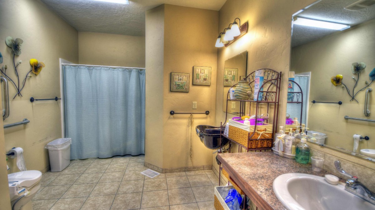 A well-lit bathroom featuring a sink, mirror, and shower curtain with decorative elements.