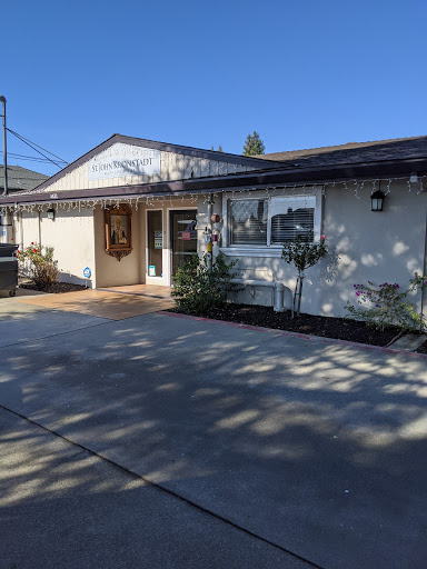 A charming residential house with a well-maintained driveway and front yard, set against a clear blue sky.