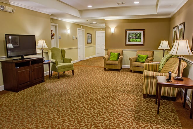 A cozy lobby featuring comfortable seating, a patterned carpet, and warm lighting.