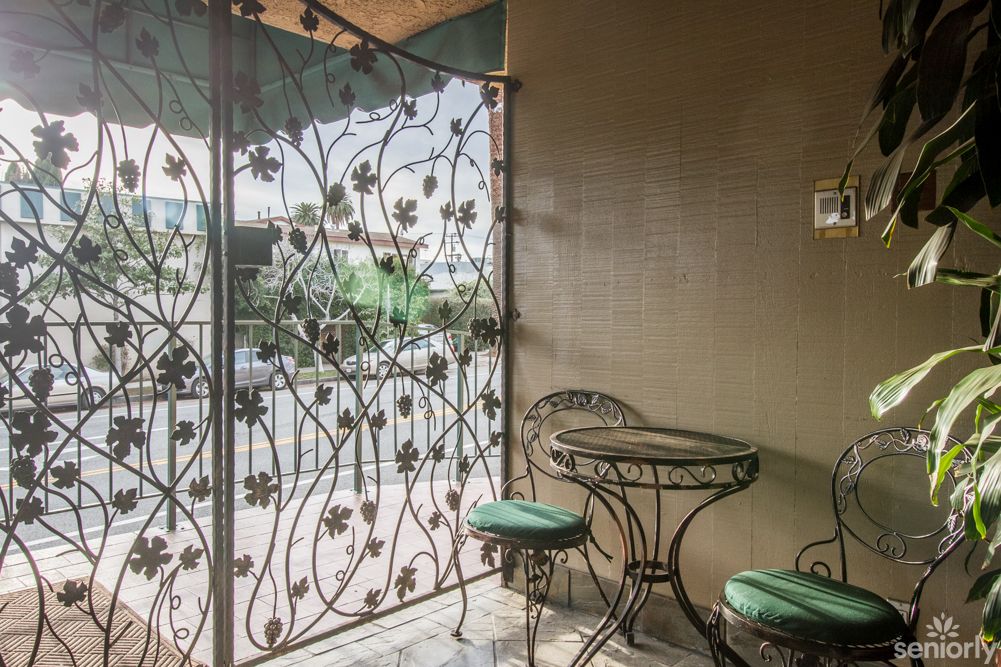A cozy balcony with wrought iron furniture and decorative railing.