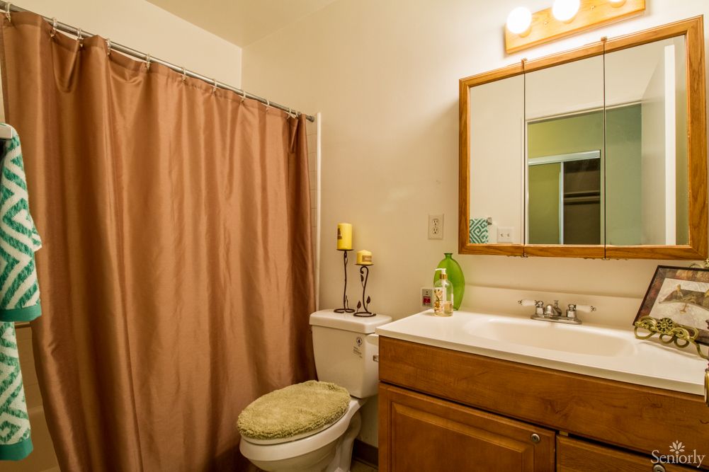 A cozy bathroom with a shower curtain, sink, mirror, and decorative candles.