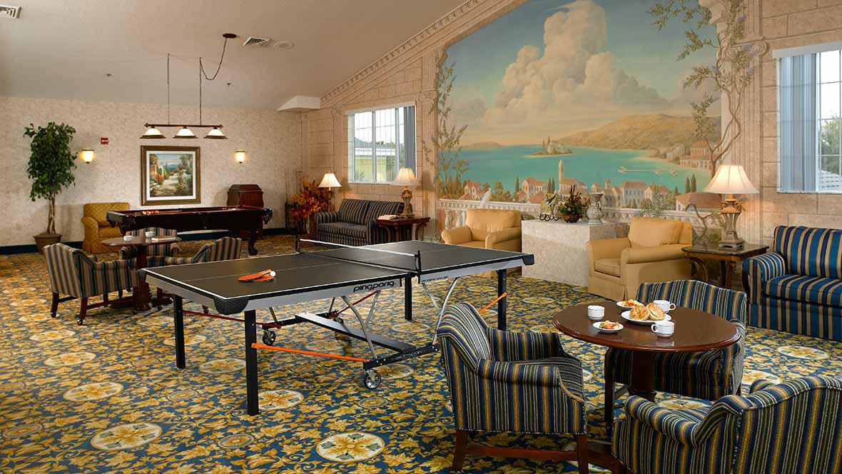 A cozy game room featuring a ping pong table, grand piano, and a seating area with a scenic mural on the wall.