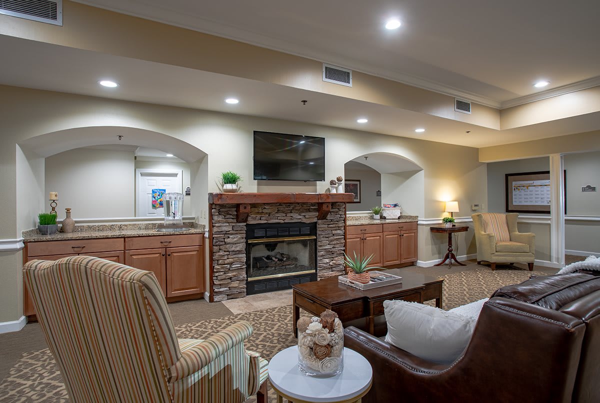 A cozy living room featuring a stone fireplace, television, and comfortable seating arrangements.