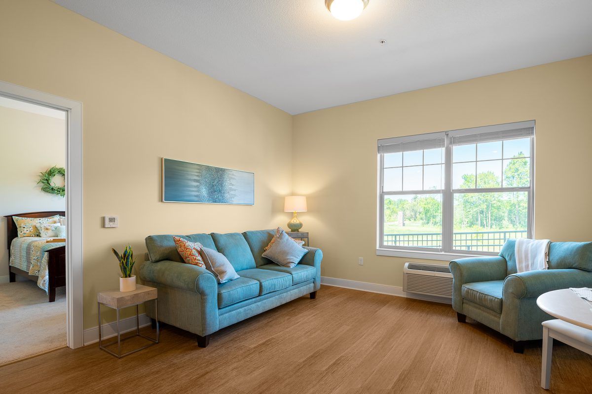 A cozy living room with a blue sofa, matching armchair, and wooden flooring.