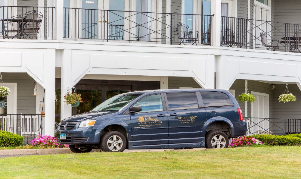 A blue van parked in front of a white building.