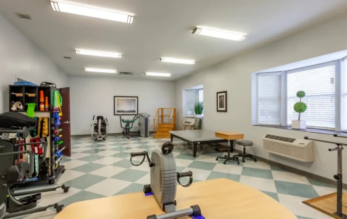 A spacious rehabilitation room equipped with therapy and exercise equipment.