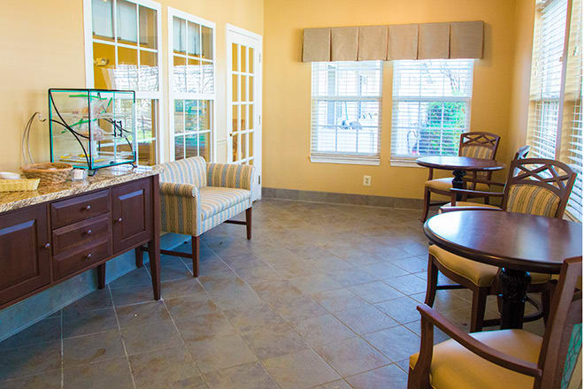 A cozy waiting room with chairs, tables, and large windows.