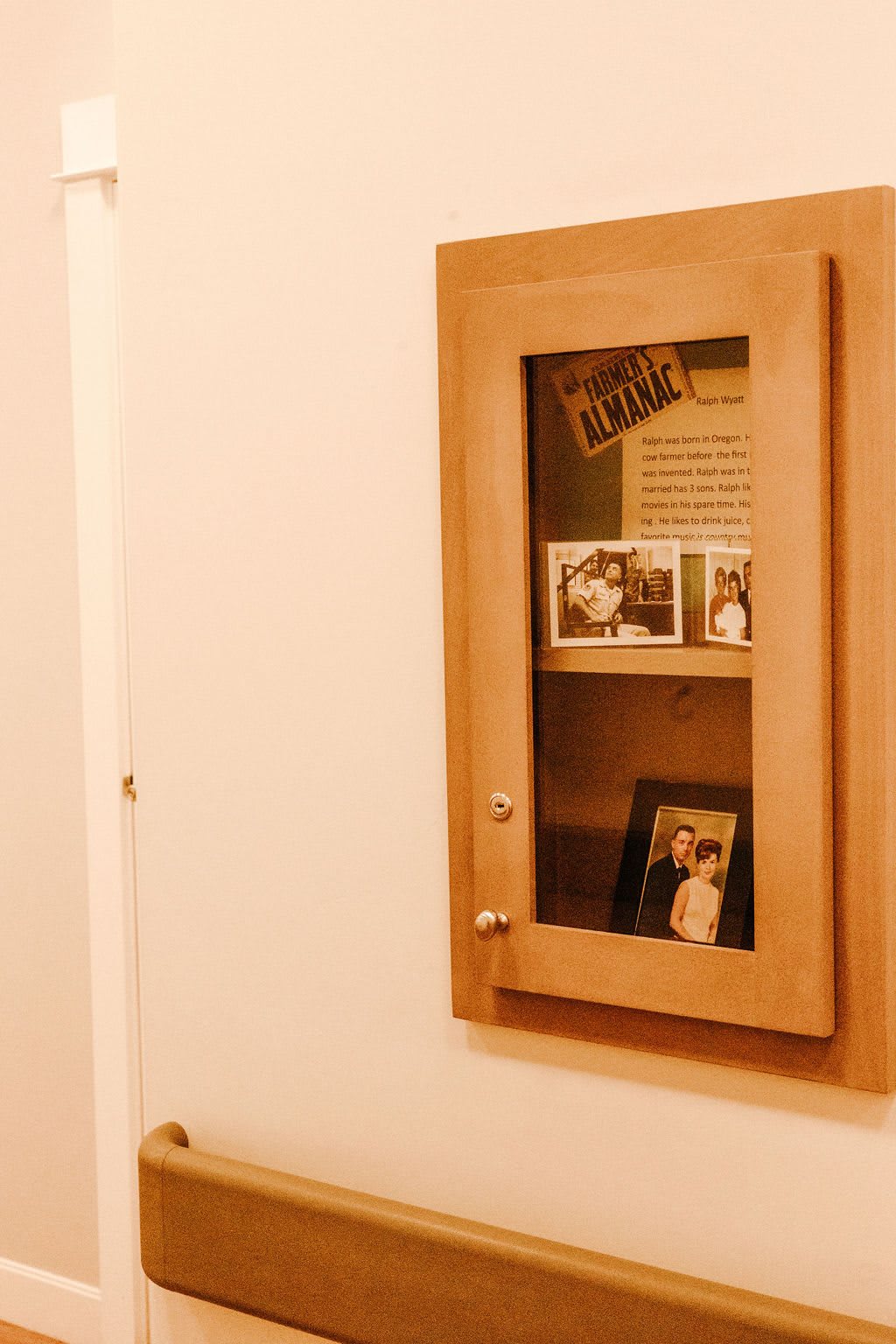 A wall-mounted wooden cabinet displaying framed photos.