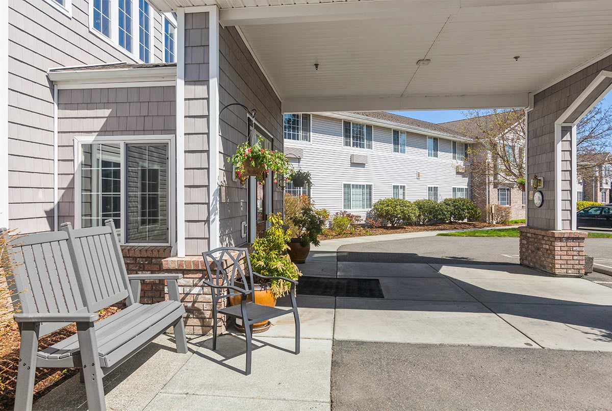 A welcoming entrance to a residential building with benches and plants.