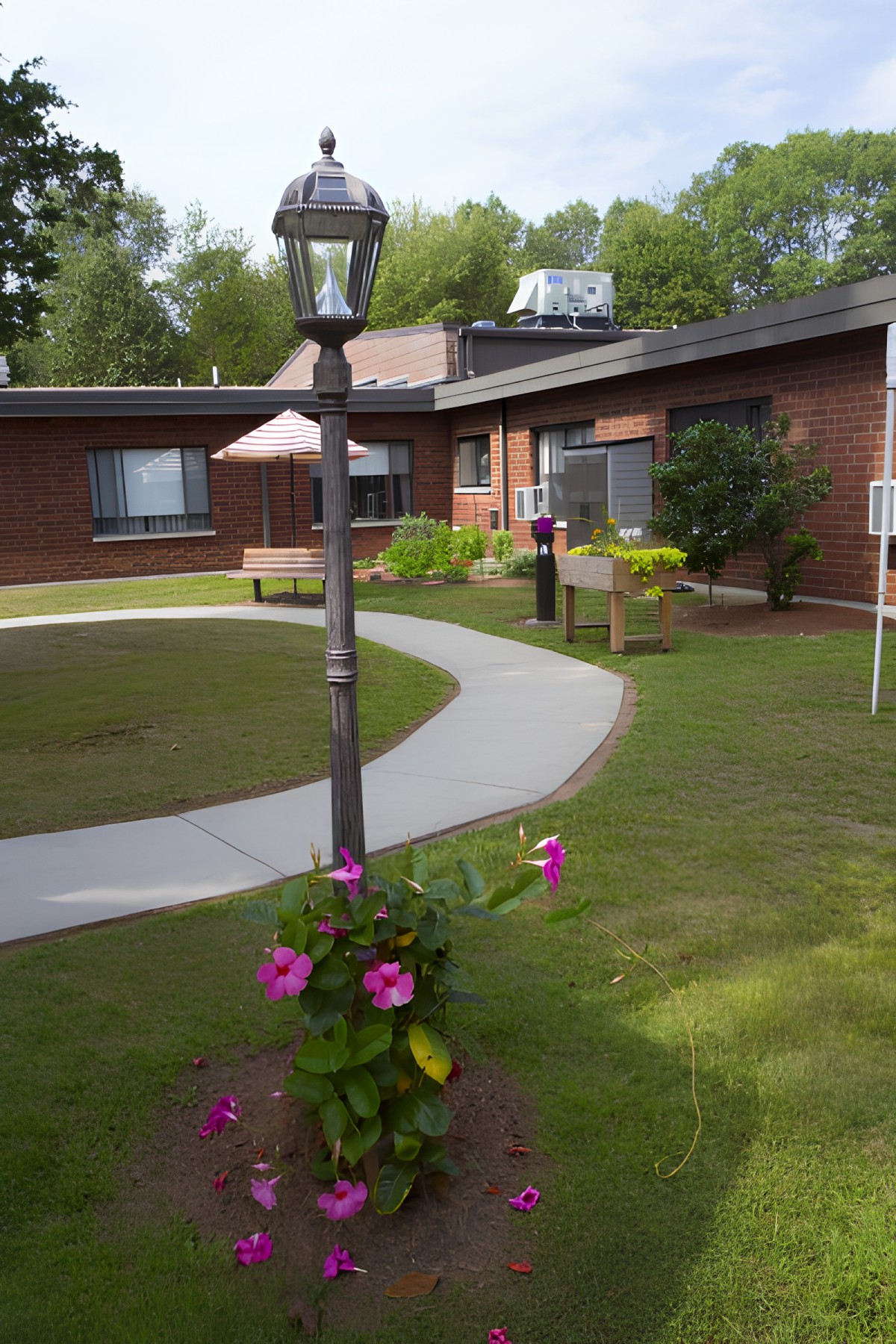 A peaceful courtyard with a garden and walking path surrounded by a brick building.