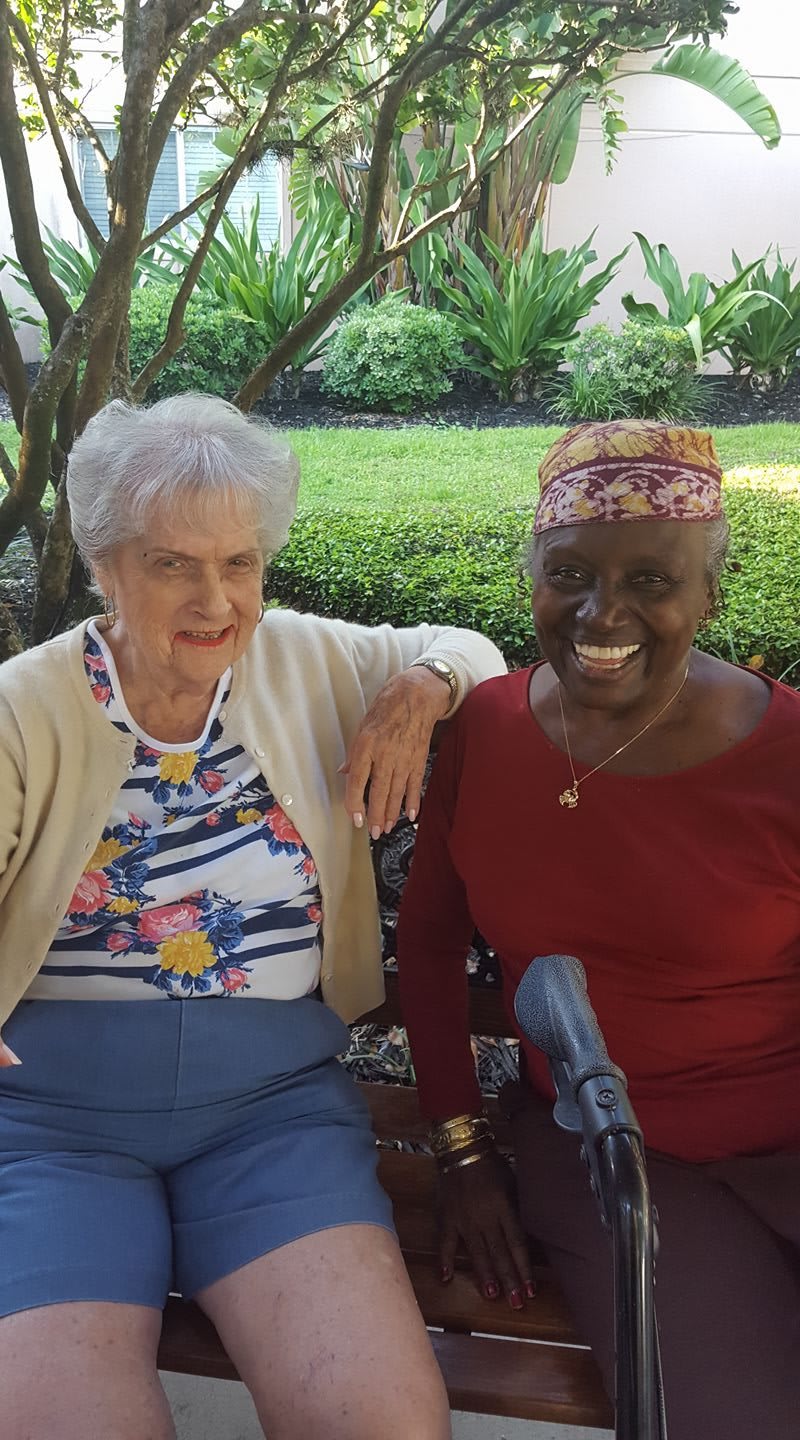 Two elderly women smiling and enjoying their time together outdoors.