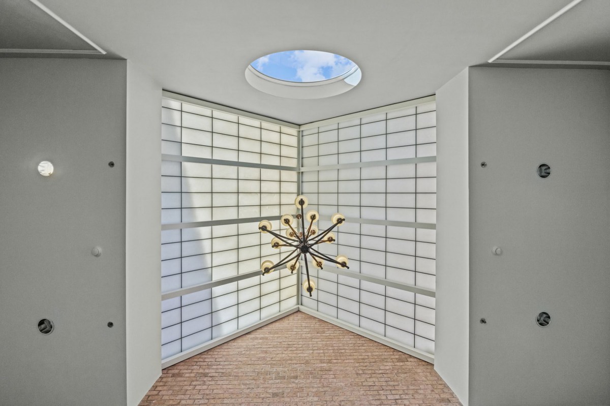 A modern, minimalist interior featuring a unique lighting fixture and a skylight.