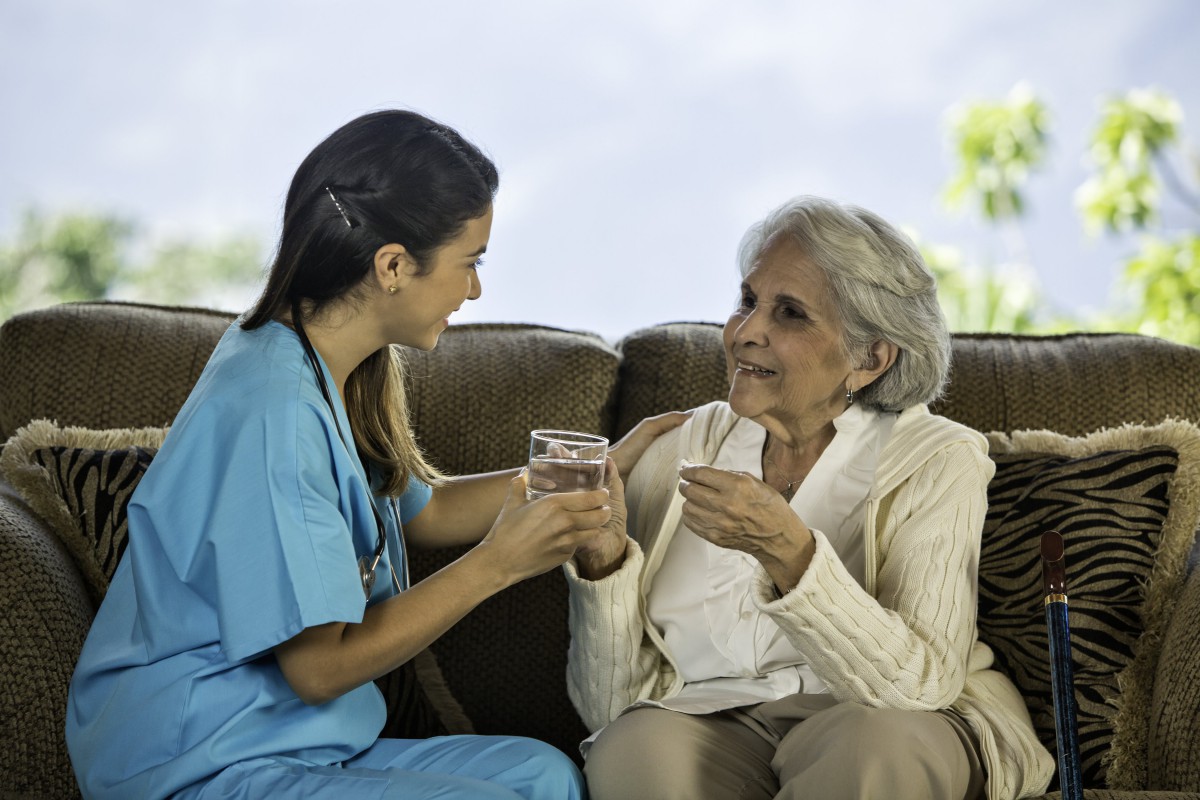 A nurse providing assistance to an elderly woman at home.