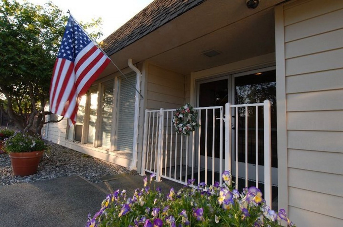 A house entrance adorned with an American flag and vibrant flowers.
