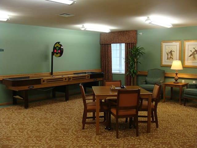 A cozy room with a table and chairs, featuring a shuffleboard game along the wall.