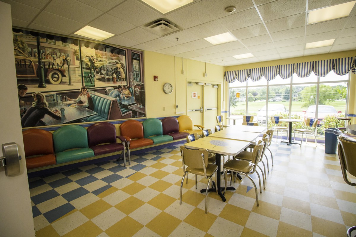 A retro-themed diner interior with colorful seating and checkered flooring.