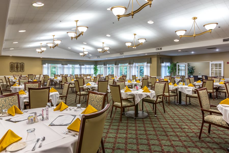 A well-lit dining area with neatly arranged tables and chairs, set for service.
