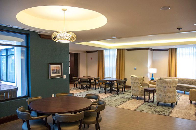 A cozy and modern dining area with elegantly arranged tables and chairs, illuminated by stylish lighting.